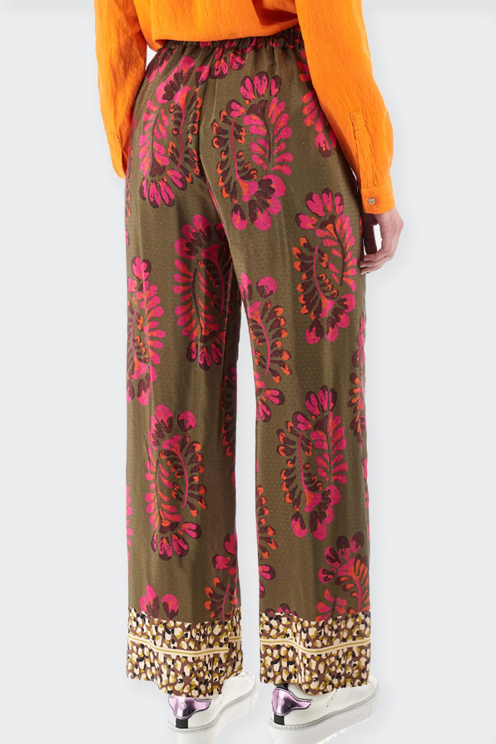 Women's palazzo trousers in satin viscose fabric. Rich floral prints and bright details on the bottom in contrasting tones recal
