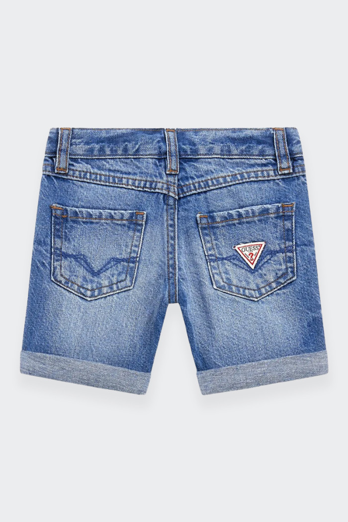 Bermuda Guess di jeans per bambino con cinque tasche e il fondo con risvolto offrono funzionalità e stile. La patch logo applica