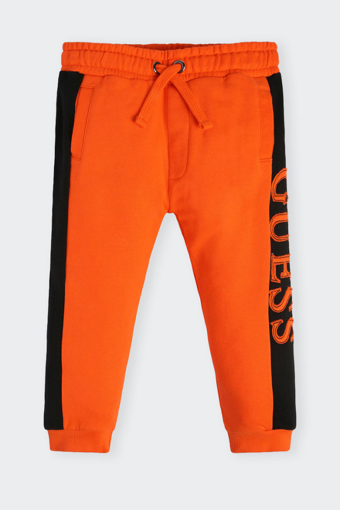 Orange sweatpants for children made of cotton. Elastic waistband with drawstring and leg with elastic at bottom. Side logo on bo