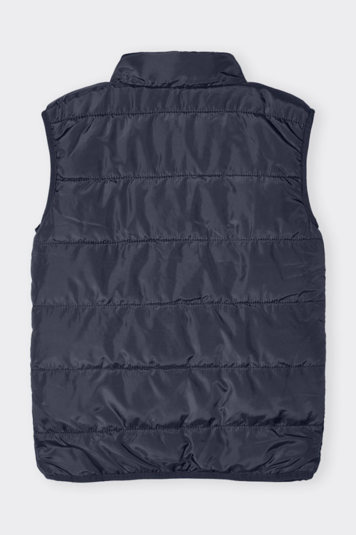 Unisex blue 100 gram sleeveless down jacket for boys and girls. Zipper closure and high mandarin collar. Ideal for coping with m
